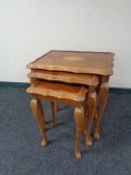 A nest of three inlaid yew wood glass topped tables