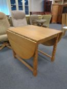 A blond oak drop leaf dining table