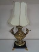 An early twentieth century ornate brass table lamp depicting swans in flight above cherubs on black