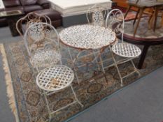A folding cast metal patio table with two chairs together with a further pair of folding metal