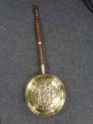 An antique brass embossed bed warming pan with a barley twist handle.
