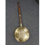 An antique brass embossed bed warming pan with a barley twist handle.