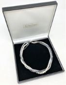 A triple strand of three-tone cultured pearls, on sterling silver clasp, total length 46 cm.
