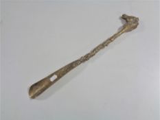 A heavy brass shoe horn with horse head handle