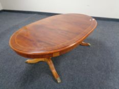 An oval inlaid mahogany coffee table with under stretcher and brass capped feet.