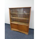 A mid 20th century sliding glass door bookcase fitted sliding doors beneath