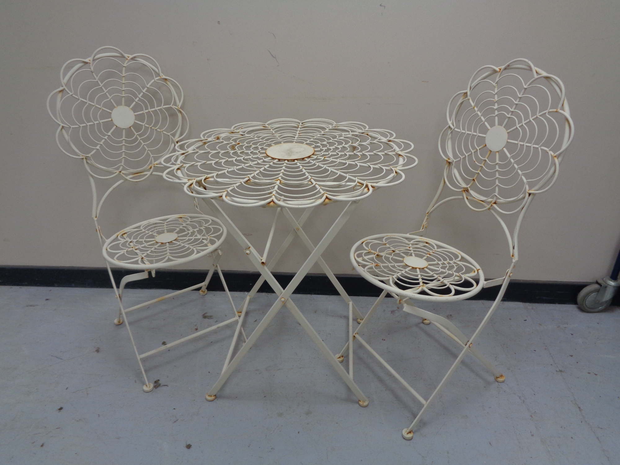A folding metal patio table and two chairs (white).