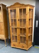 A shaped pine glazed display cabinet on bun feet