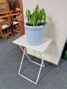 A Convallaria plant in glazed pot together with a folding metal table.