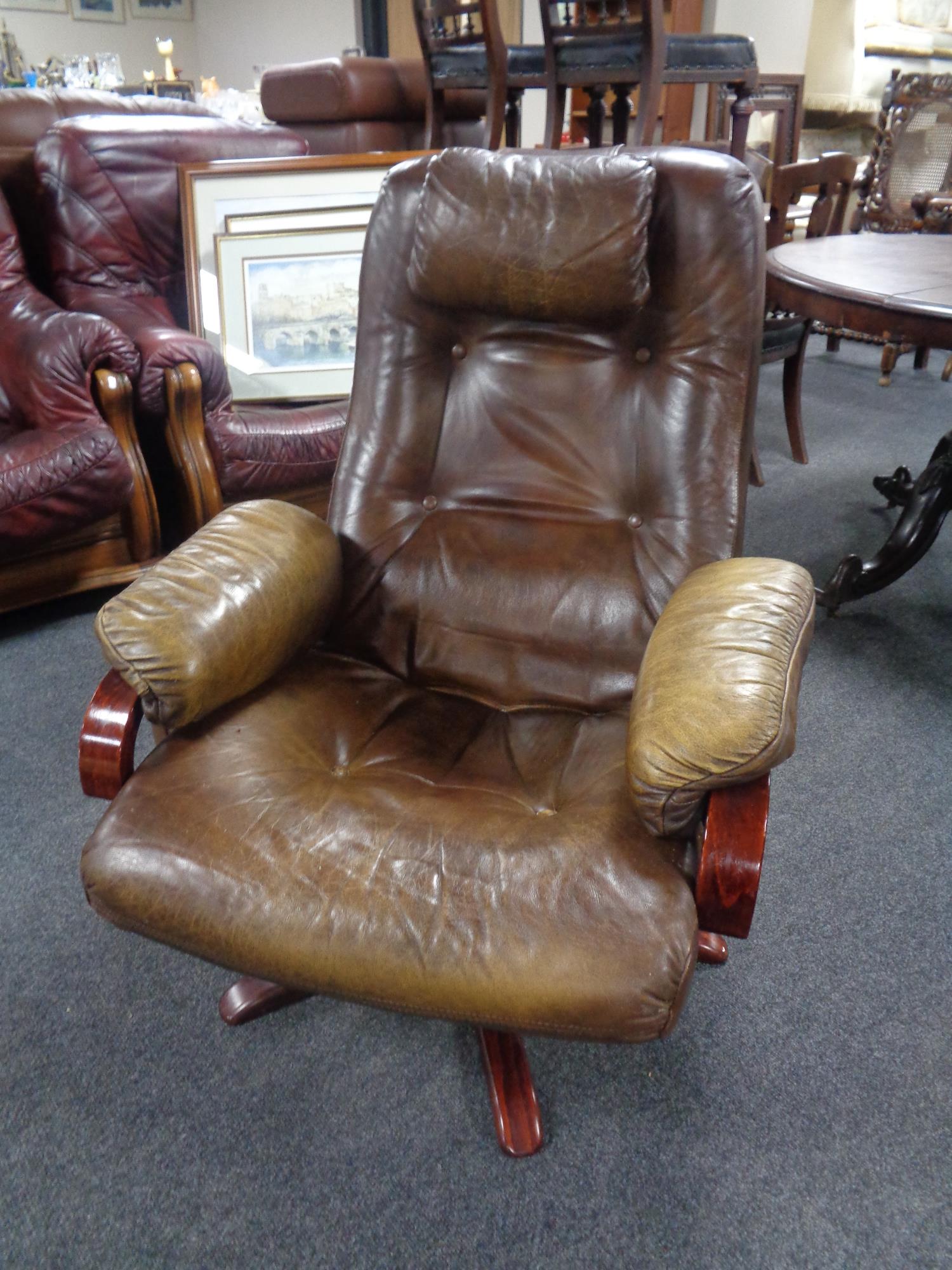 A 20th century beech framed swivel armchair upholstered in a brown button leather.