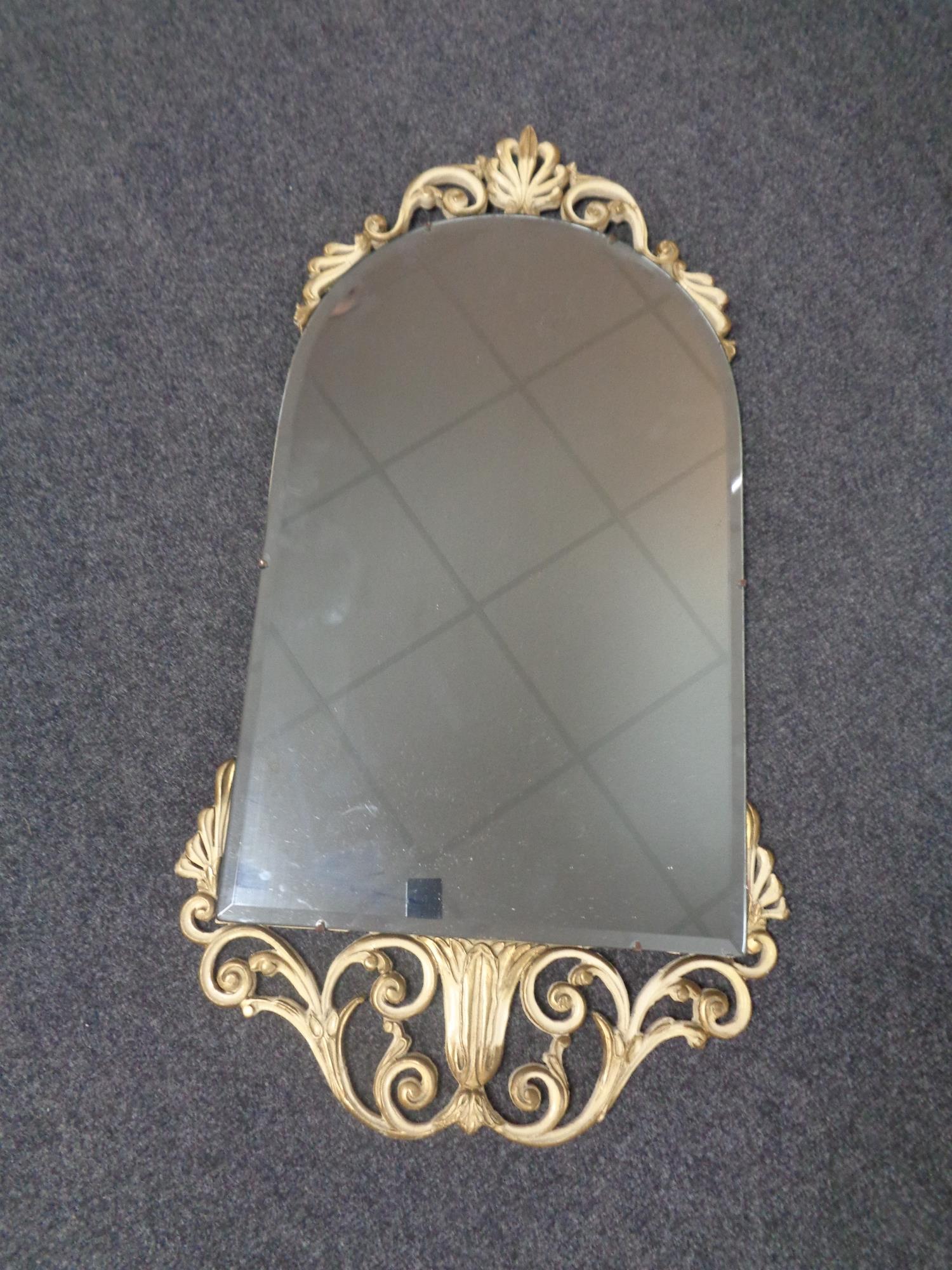 A cream and gilt framed arch topped bevel edged mirror.