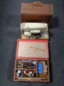 A cased 20th century Singer electric sewing machine and a case of sewing accessories