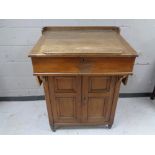 An antique oak clerk's desk fitted a double door cupboard beneath