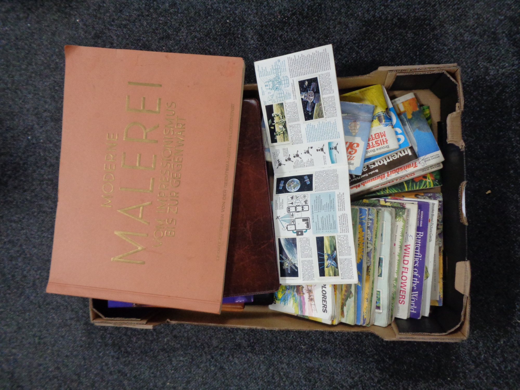 A box containing United Kingdom and German tea cards in albums.