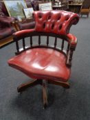 A red buttoned leather swivel captain's armchair