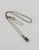 A silver pendant on chain set with emerald and white topaz.