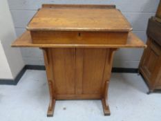 An antique oak clerk's desk fitted cupboard to rear