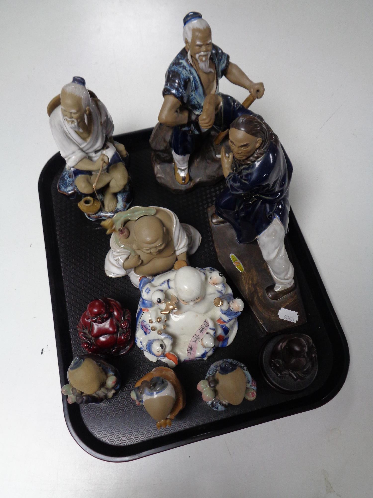 A tray containing Eastern ceramic and resin figures to include Buddha's, fisherman, etc.