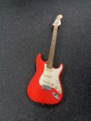 A red Squier Strat electric guitar.