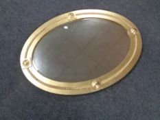 An Edwardian oval bevel edged mirror in a painted gilt frame.