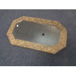 An early 20th century octagonal brass embossed framed bevel edged mirror.