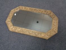 An early 20th century octagonal brass embossed framed bevel edged mirror.