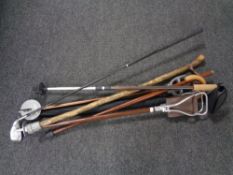 A bundle of assorted walking sticks together with a shooting stick and golf club