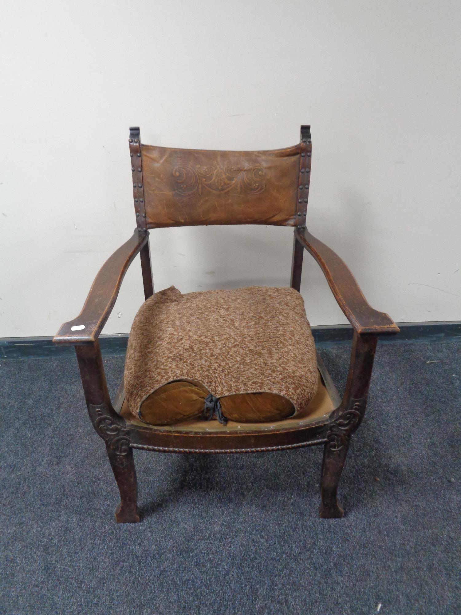 An oak framed Arts & Crafts armchair with a tooled leather back.