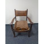 An oak framed Arts & Crafts armchair with a tooled leather back.