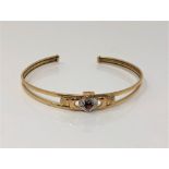 A gold, garnet and diamond set Claddagh bangle, apparently unmarked.