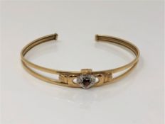 A gold, garnet and diamond set Claddagh bangle, apparently unmarked.