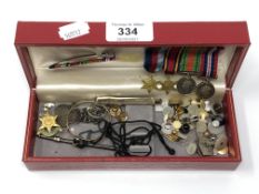 A box containing silver swizzle stick (a/f), miniature WWII medals, monocle,