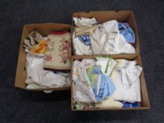 Two boxes of assorted table linens to include needlework pieces,