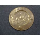 A circular brass embossed plaque depicting two lions and shield,