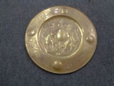 A circular brass embossed plaque depicting two lions and shield,