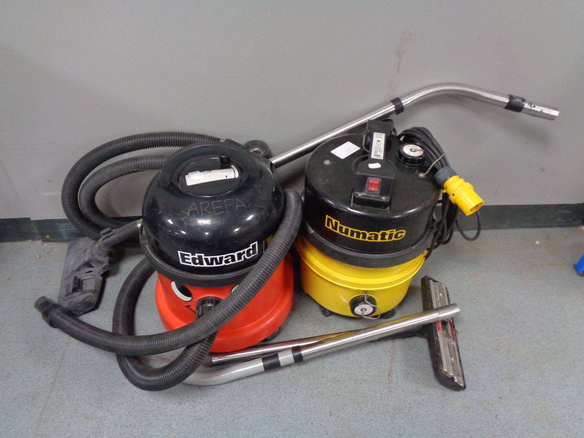 A Numatic and an Edward 110V commercial vacuums with hoses and accessories.