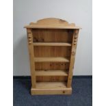 A set of narrow stripped pine open bookshelves.