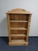 A set of narrow stripped pine open bookshelves.