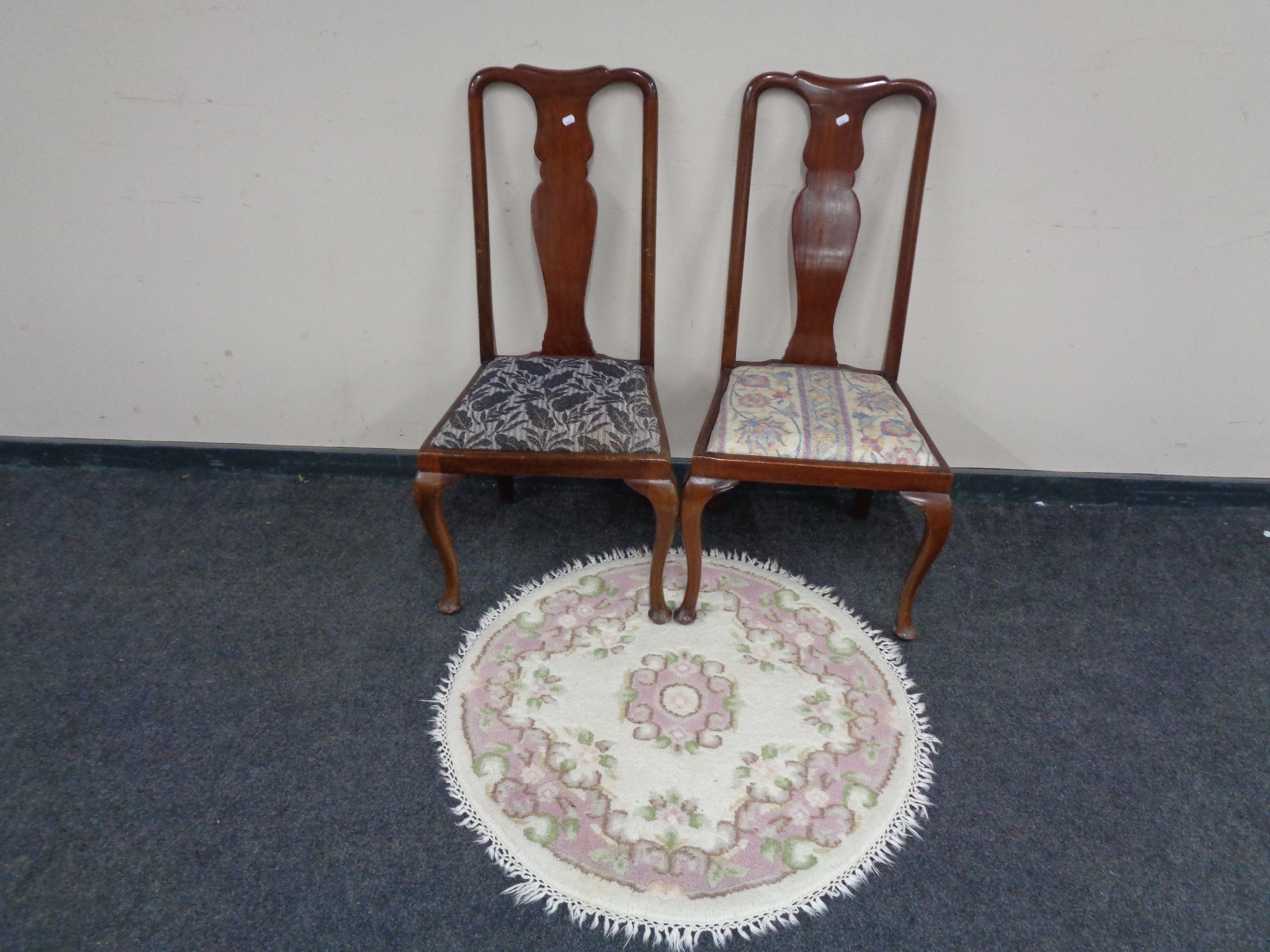 A pair of mahogany Queen Anne style dining chairs together with a circular fringed Indian rug.