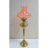 A 19th century brass oil lamp with pink glass shade and chimney,