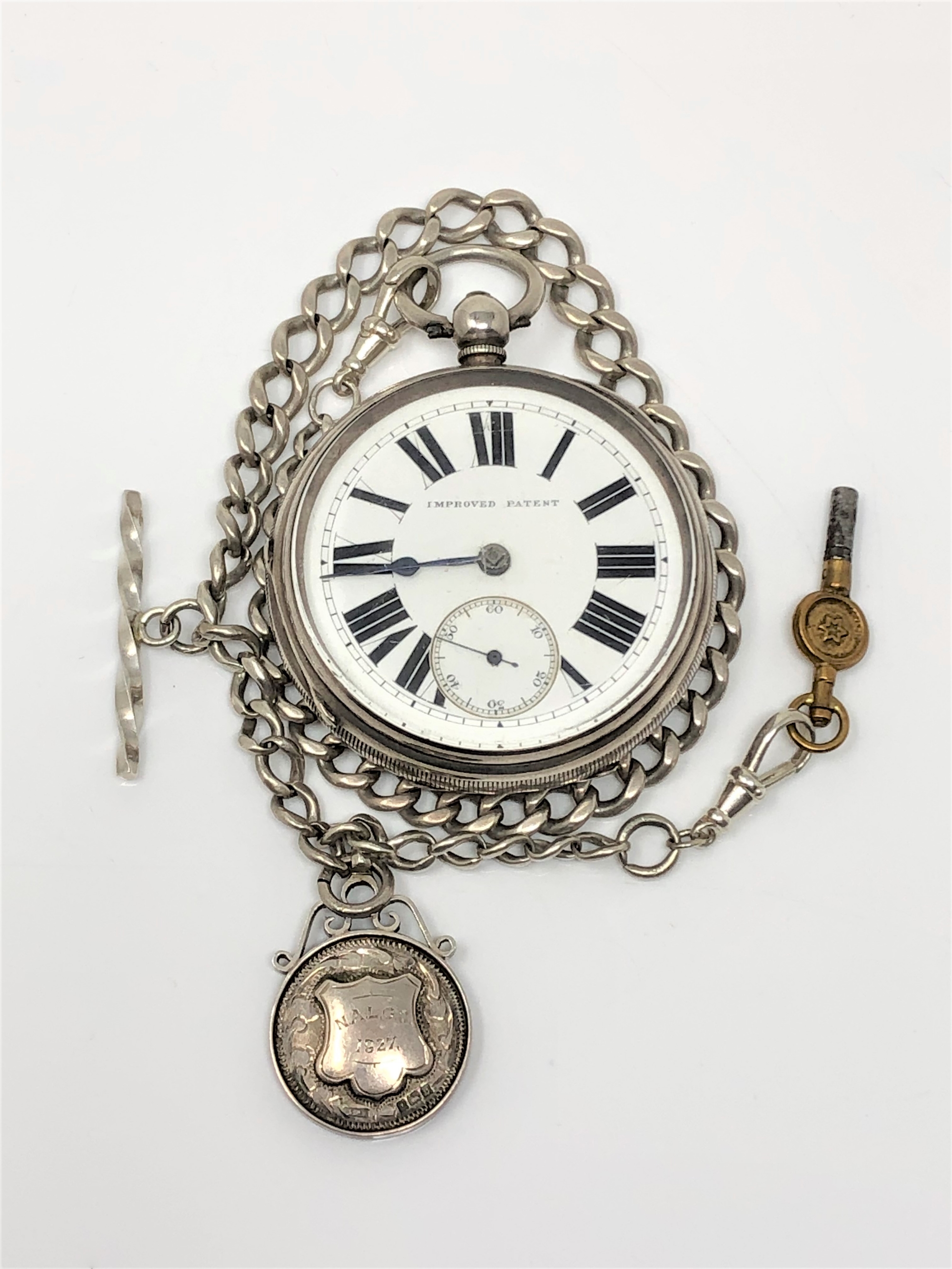 A silver open face pocket watch signed Improved Patent, on silver Albert chain with T-bar,