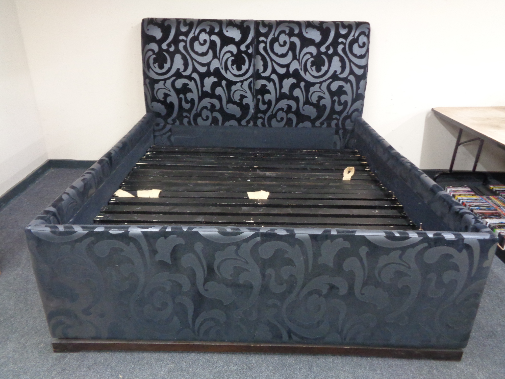 A 6ft bed frame upholstered in a black and silver fabric.