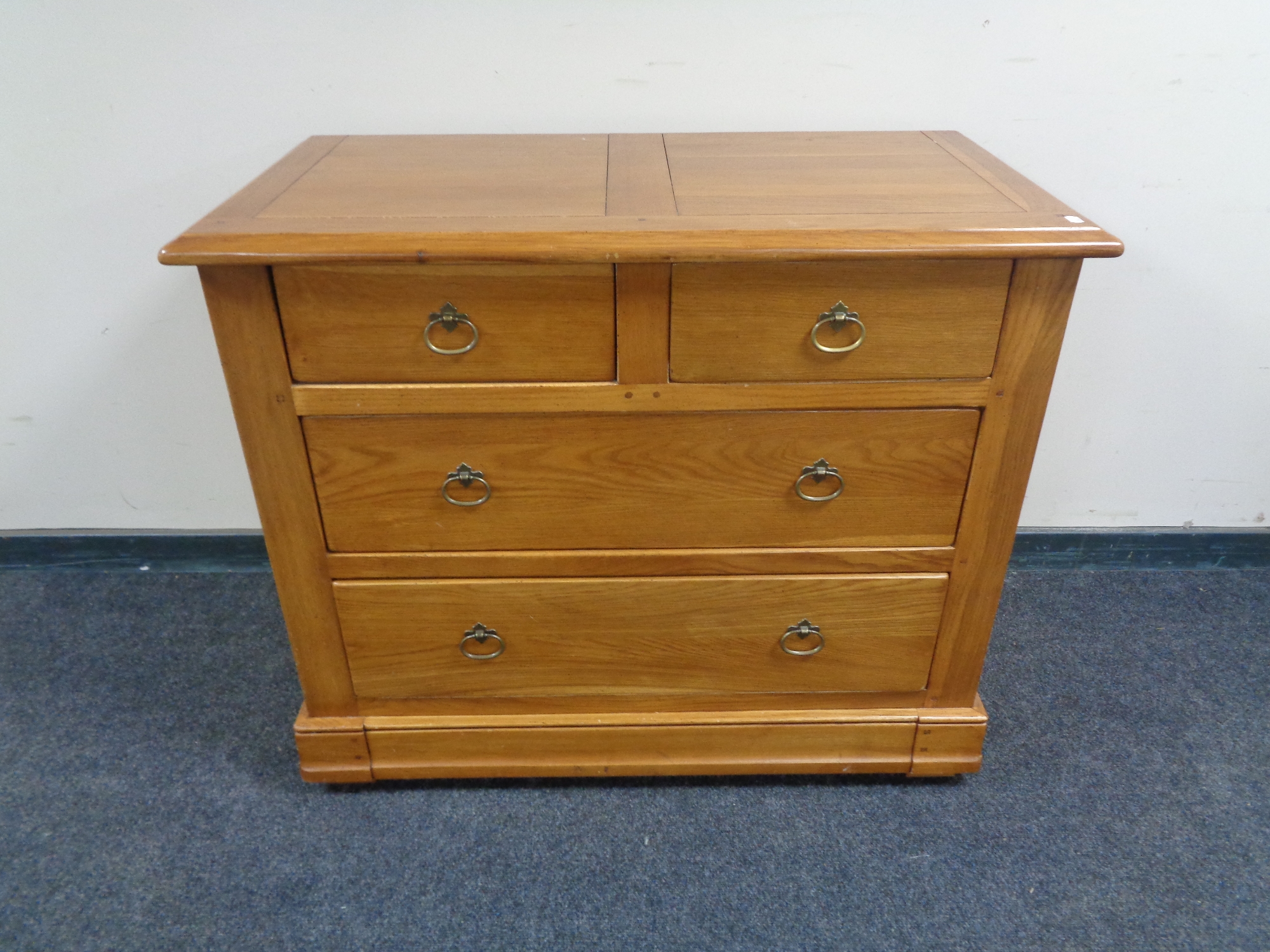 A contemporary four drawer chest with brass drop handles together with matching bedside cabinet,