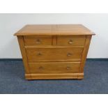 A contemporary four drawer chest with brass drop handles together with matching bedside cabinet,