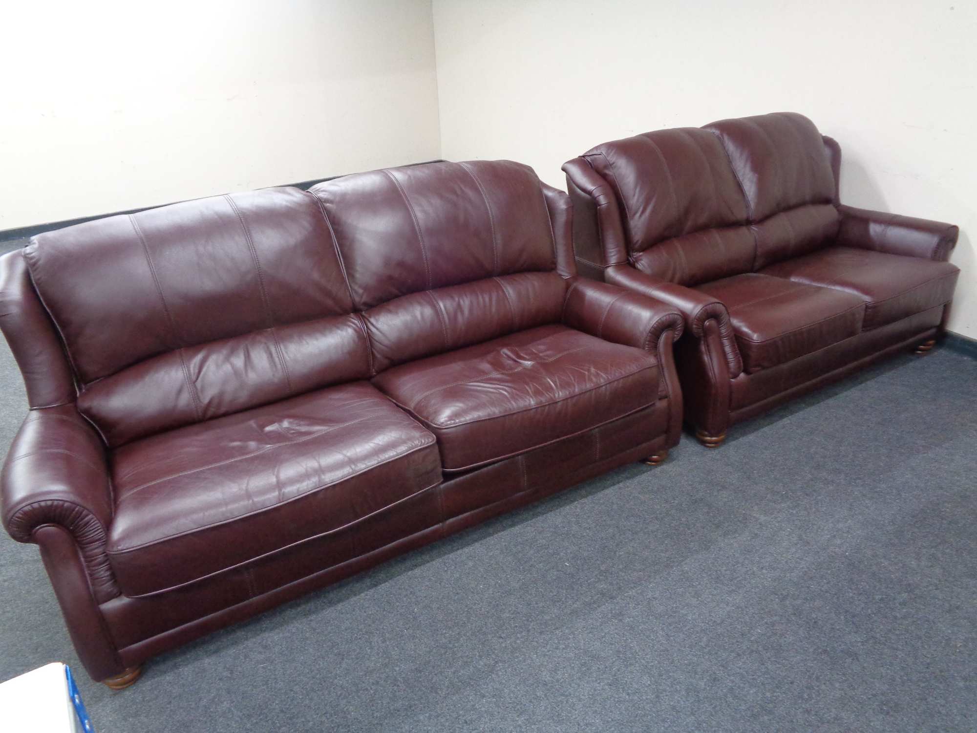 A Wade Additions Burgundy leather three seater settee with matching two seater settee.