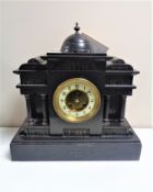 A 19th century German black slate half hour striking mantel clock with brass and enamel dial and