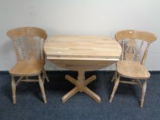 A pine drop leaf pedestal kitchen table together with two chairs.