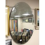 An oval all glass bevelled mirror, 61 cm x 89 cm.