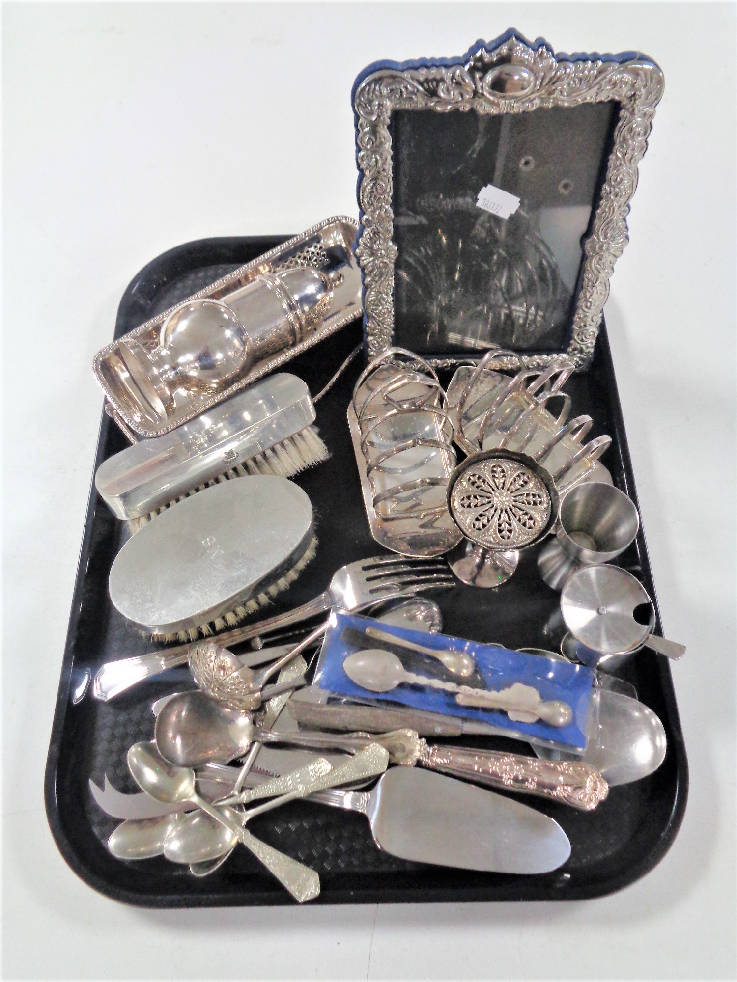 A tray containing antique and later plated wares to include photo frame, toast rack, sugar sifter,