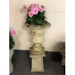 A composition stone campana urn on stand planted with Dahlias,